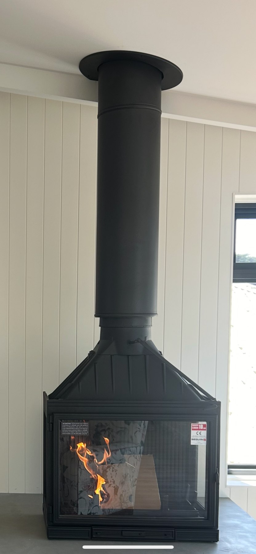 Mead Air wood fireplace with a tall black flue and a fire burning inside